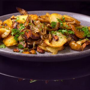 Жареный картофель с ломтиками сочной телятины, луком и белыми грибами